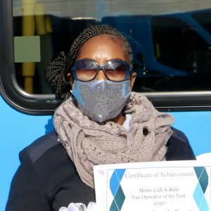 Metro Call‑A‑Ride 2020 Operator of the Year Barbara, smiling at the camera and holding her certificate of achievement